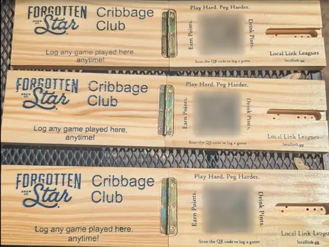 Three hinged wooden cribbage boards laser-engraved with the Forgotten Star logo, Cribbage Club, Log any game played here anytime, and a QR code